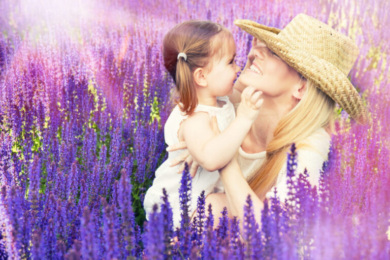 A joyful moment between a mother and child, sharing a loving embrace amidst a picturesque field of vibrant purple flowers.